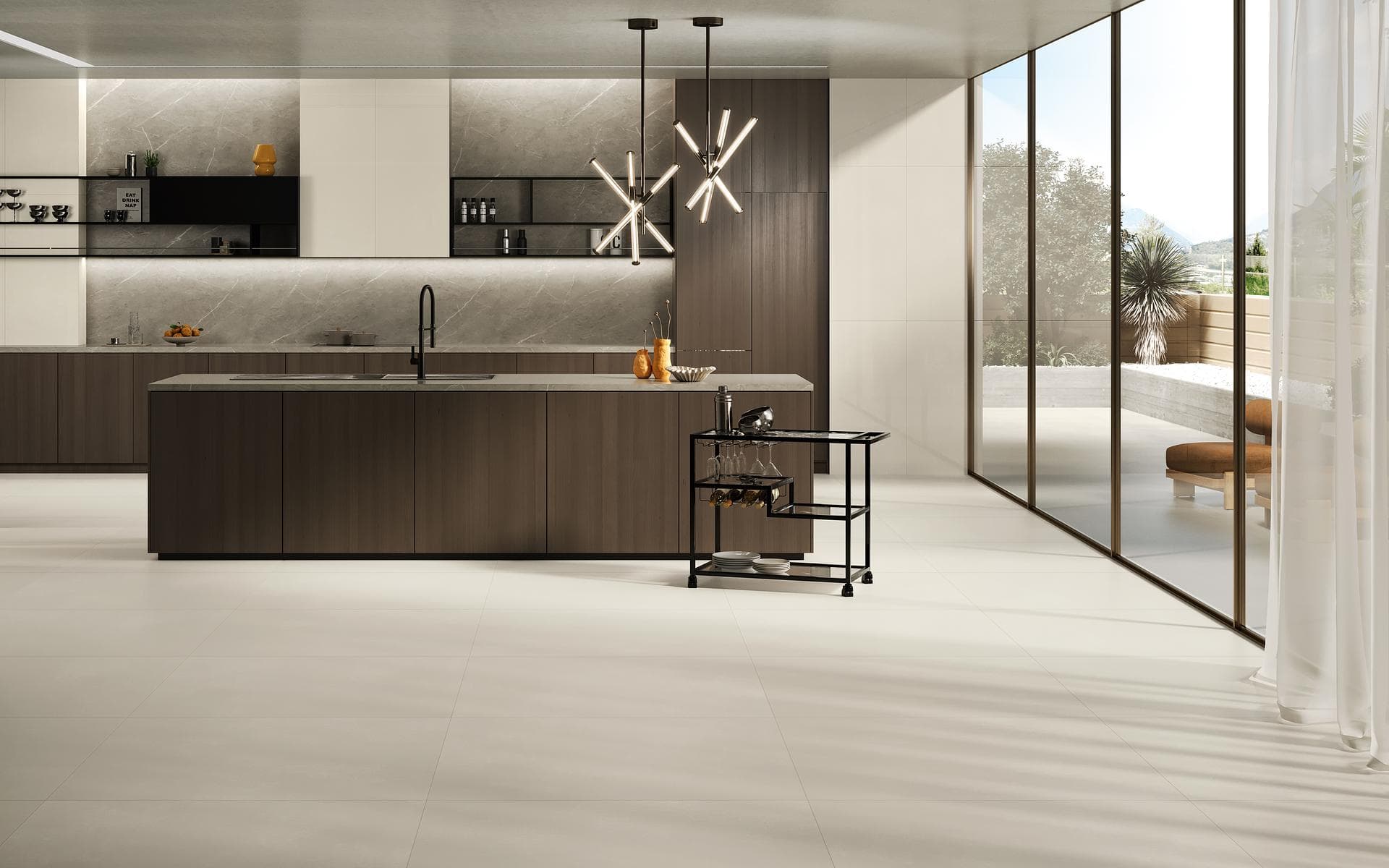 Open-plan kitchen with matt white floor Open-plan kitchen with dark wood island, matt white porcelain floor and beige walls facing the garden