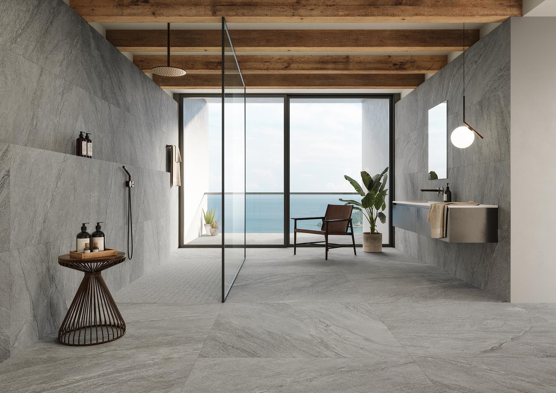 Baño efecto piedra gris oscuro con vista al mar Baño con gres efecto piedra gris oscuro mate en suelo y paredes, ducha abierta y ventanal al mar