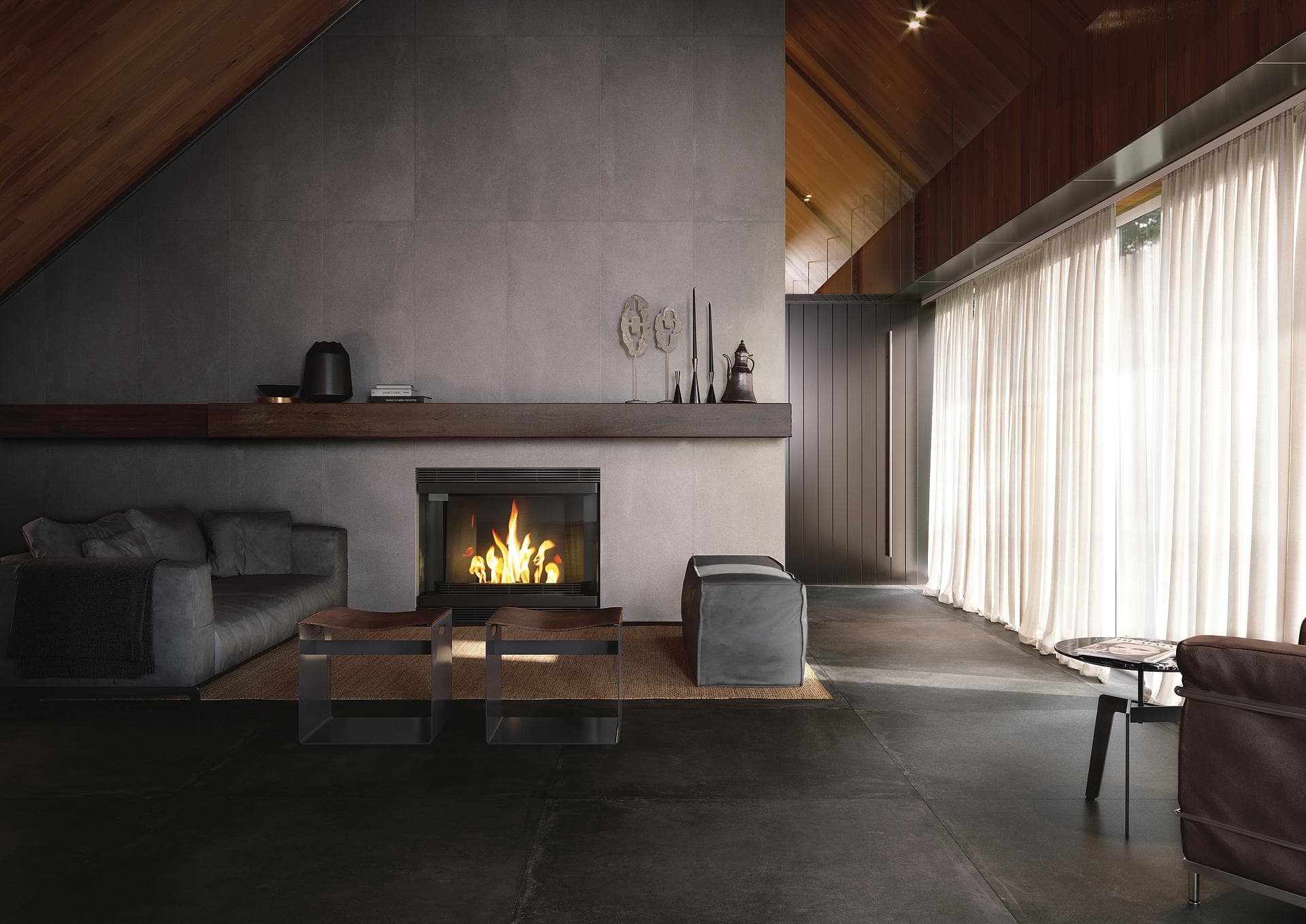 Salón con chimenea y pared efecto cemento Salón con chimenea, pared gris efecto cemento y suelo negro mate bajo techo de madera
